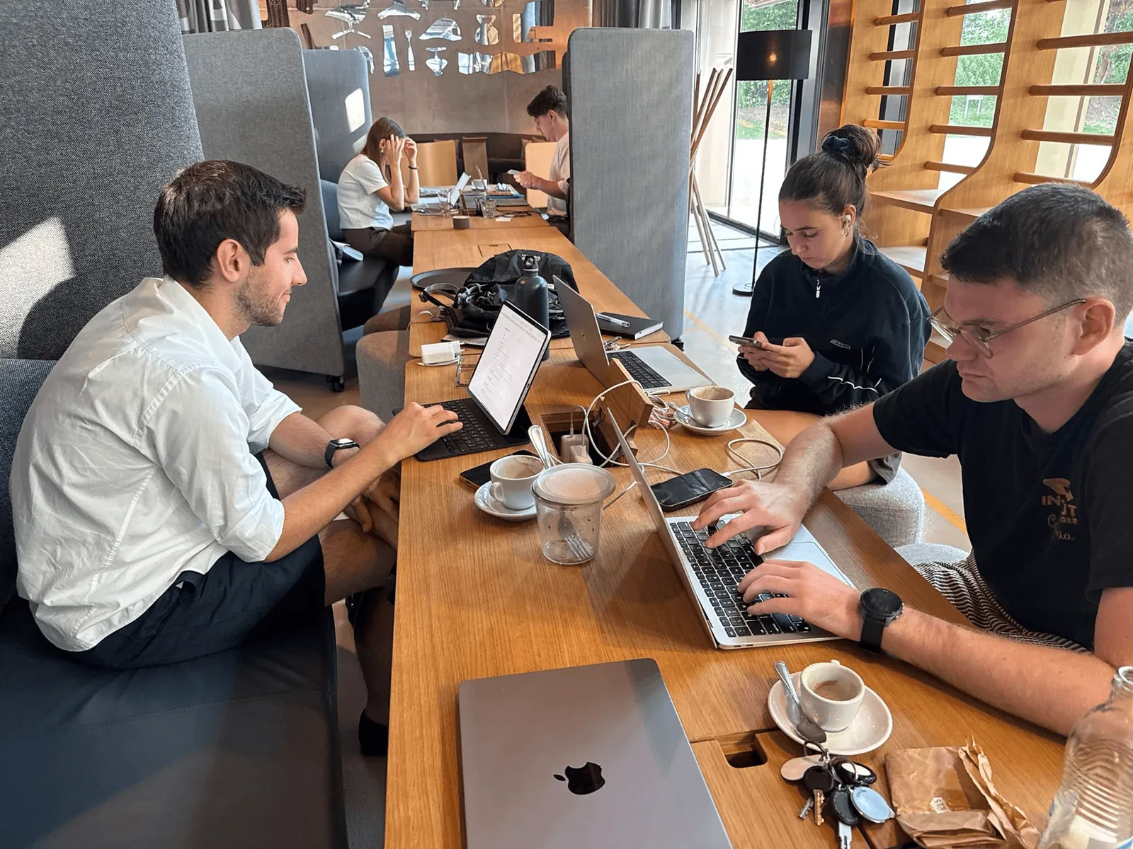 People working on laptops at a long wooden table